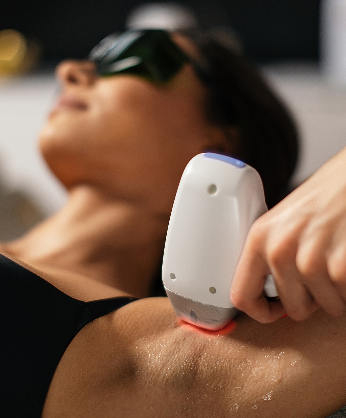 Woman using at-home laser hair removal device.