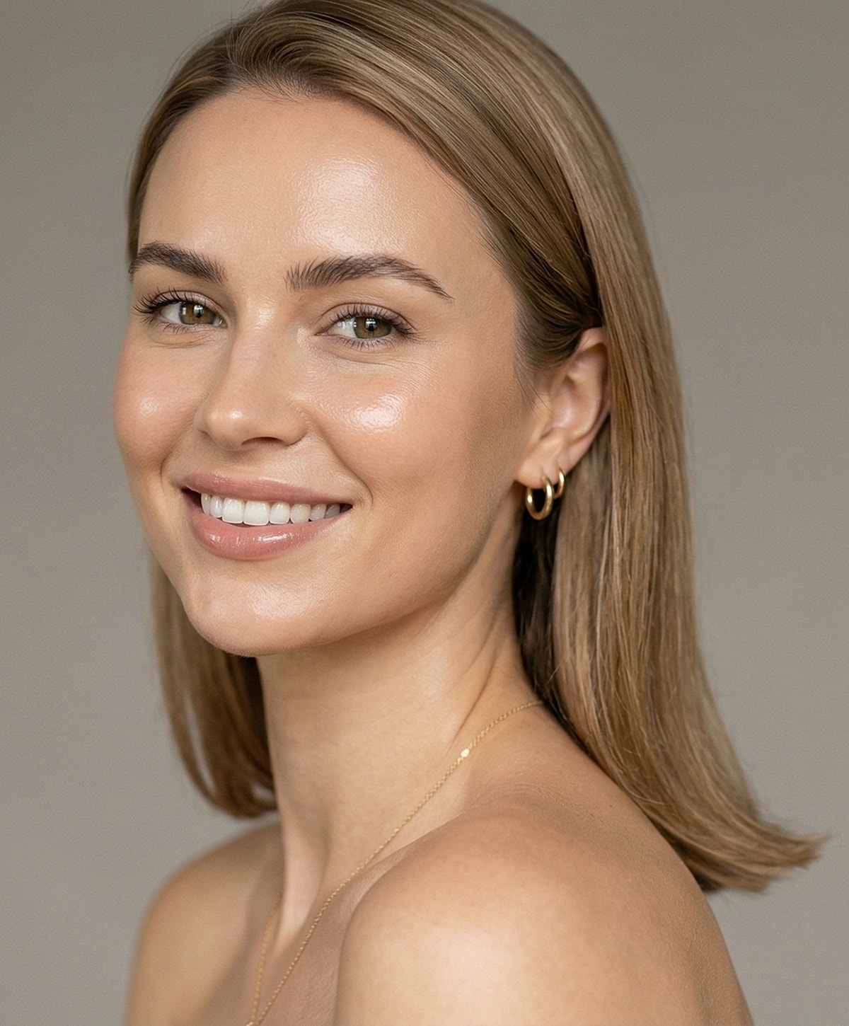 Smiling woman with natural makeup and jewelry.
