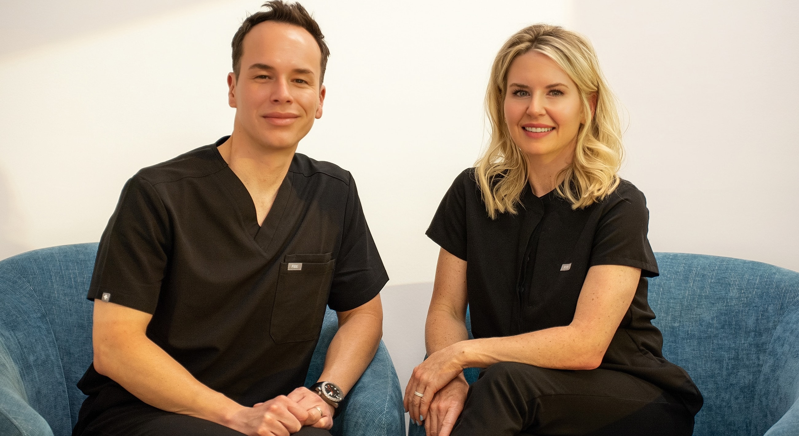Two professionals sitting together in casual attire.
