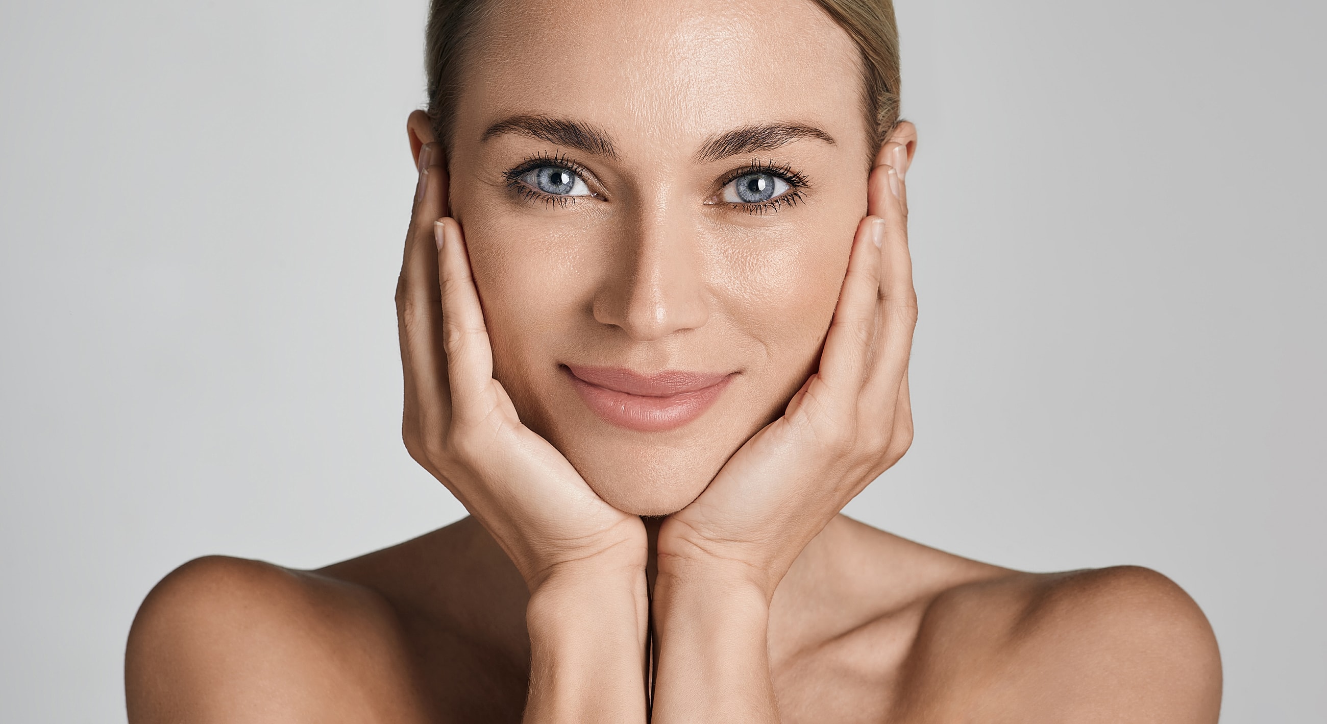 Smiling woman with hands on her face.